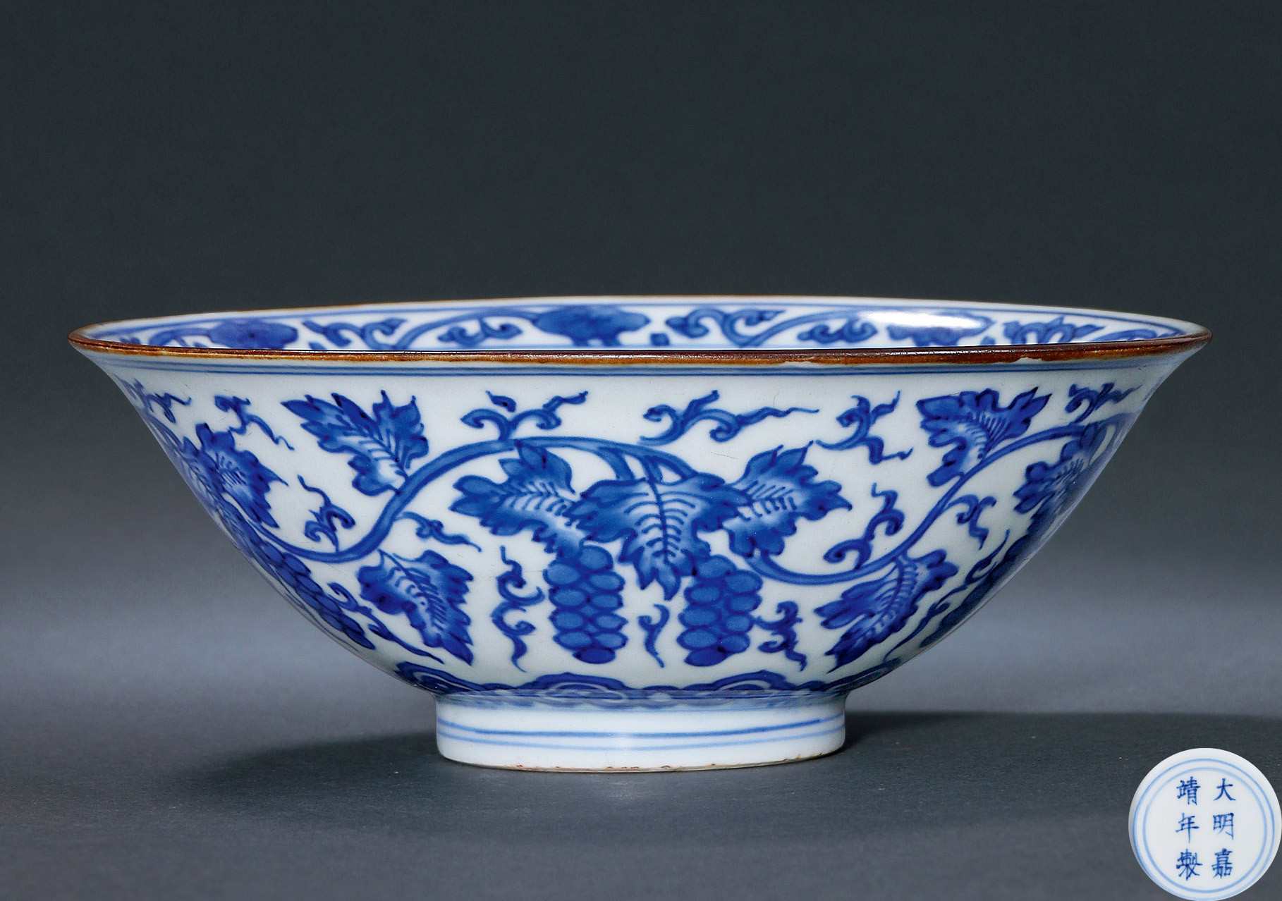 A BLUE AND WHITE BOWL WITH GRAPE DESIGN
