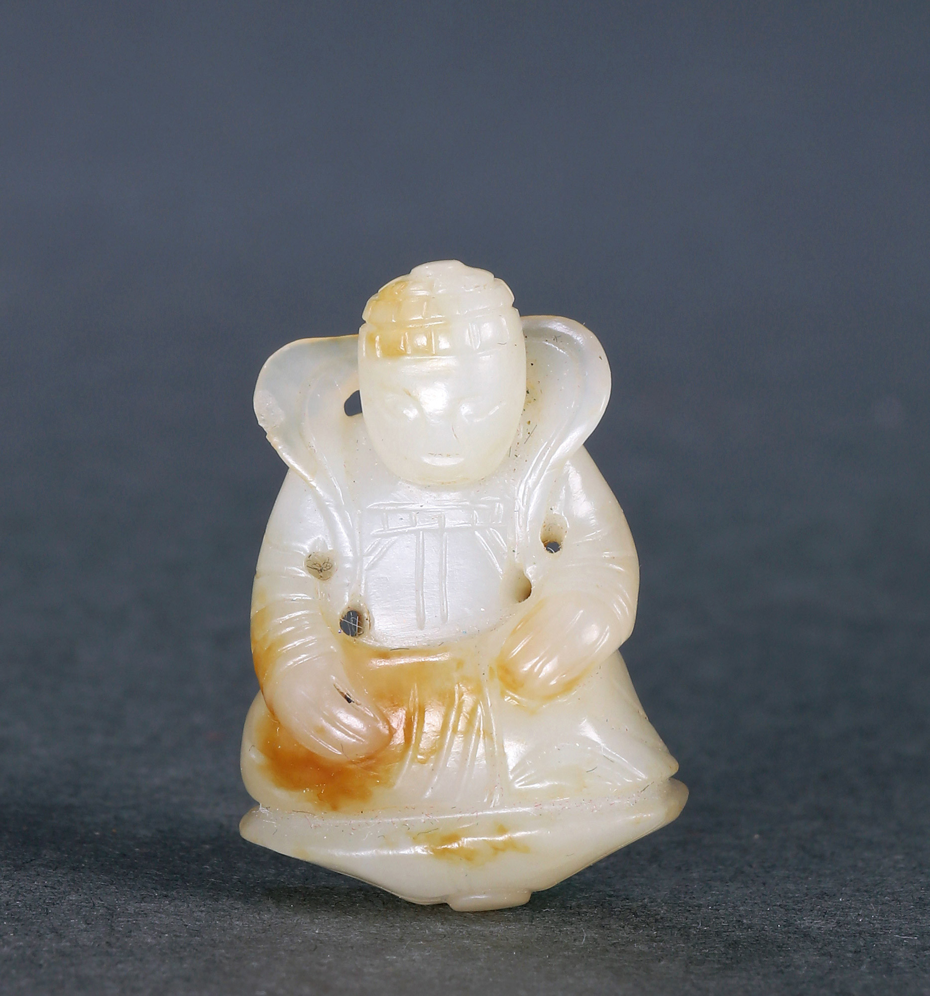 A SMALL WHITE JADE SEATED BUDDHA