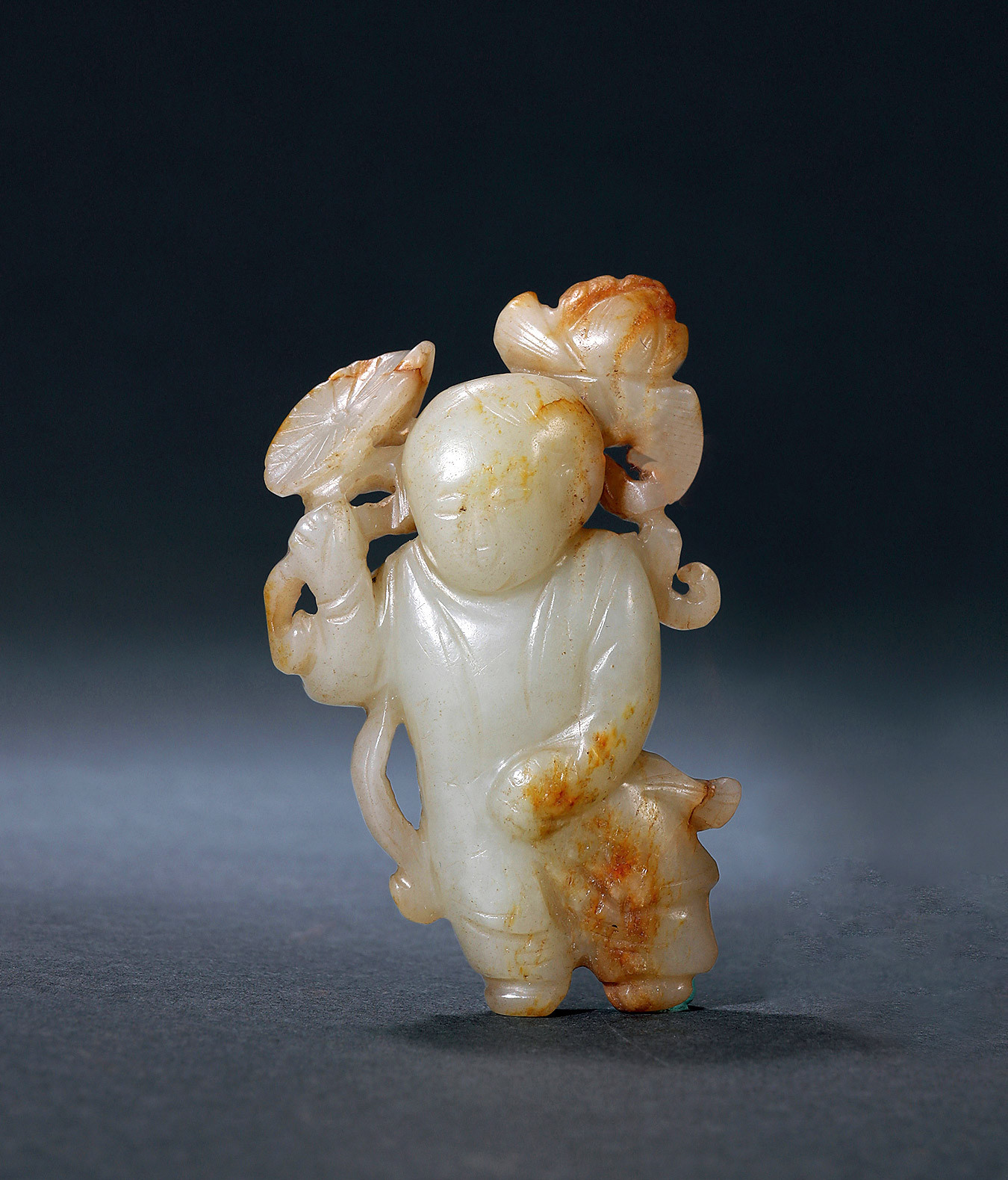 A WHITE JADE CARVING OF BOY HOLDING LOTUS