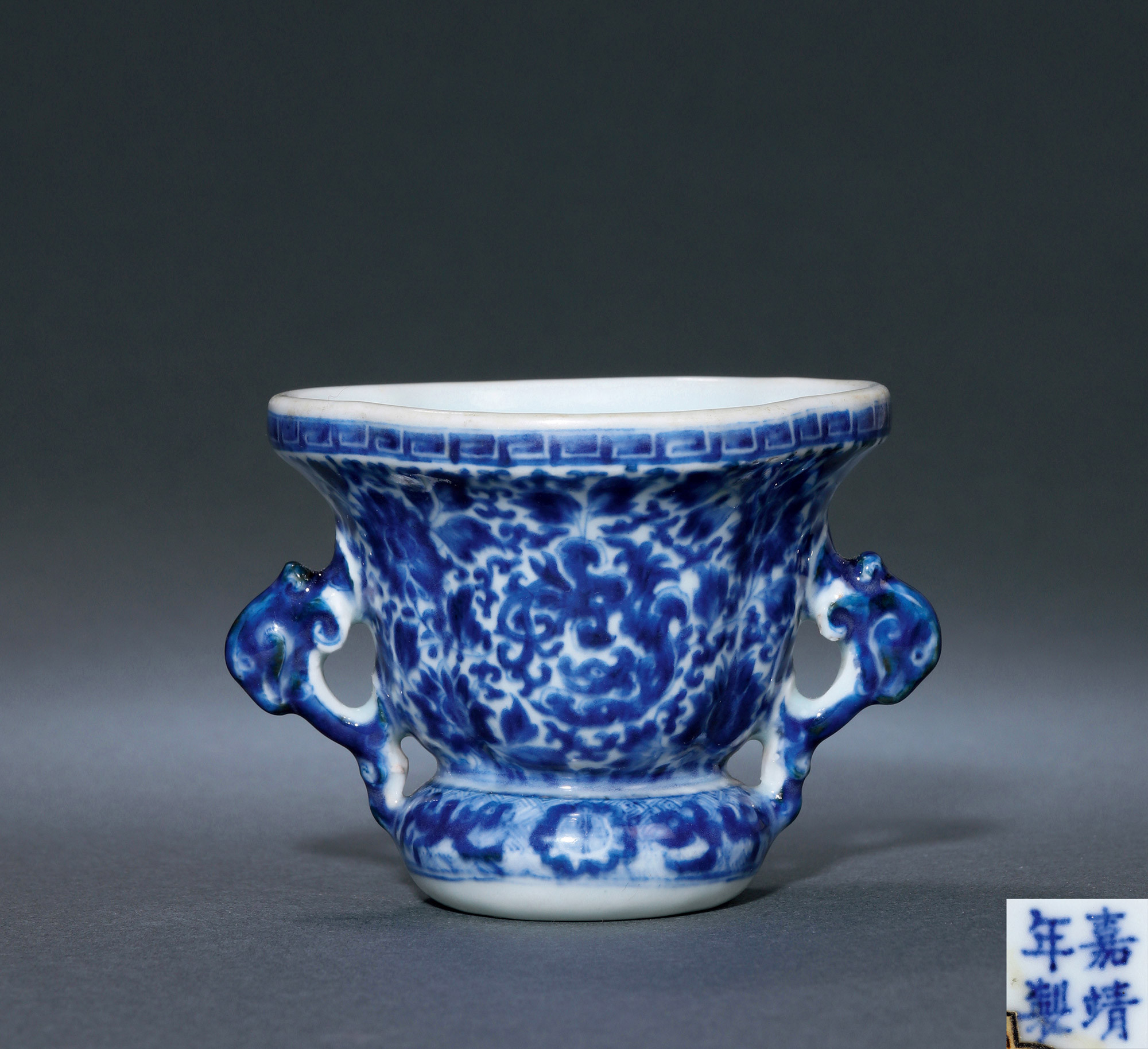 A BEGONIA-SHAPED BLUE AND WHITE CUP WITH‘DRAGON AND FLORAL’ DESIGN AND PHOENIX HANDLES