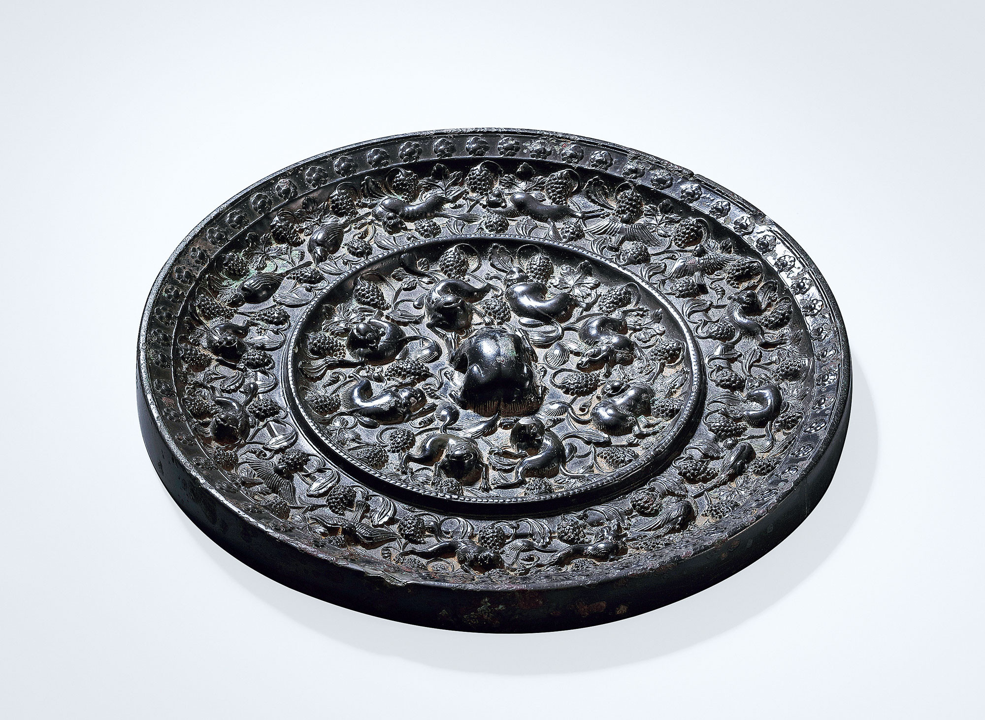 A LARGE ‘MYSTERIOUS BEASTS AND GRAPES’ BRONZE MIRROR
